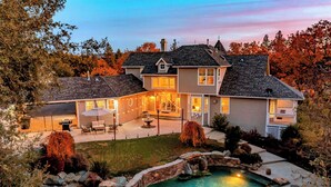 Una casa de dos pisos con piscina, zona de estar exterior y un jardín bien cuidado.