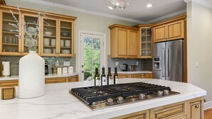 Cocina moderna con armarios de madera, una isla grande con estufa a gas y un refrigerador de acero inoxidable.