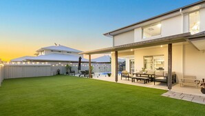 A modern house with a covered patio, a well-maintained lawn, and a visible kitchen area. - Putt Putt - Pool Slide - 100m to Beach - Ultimate Family Entertainer (Kingscliff)