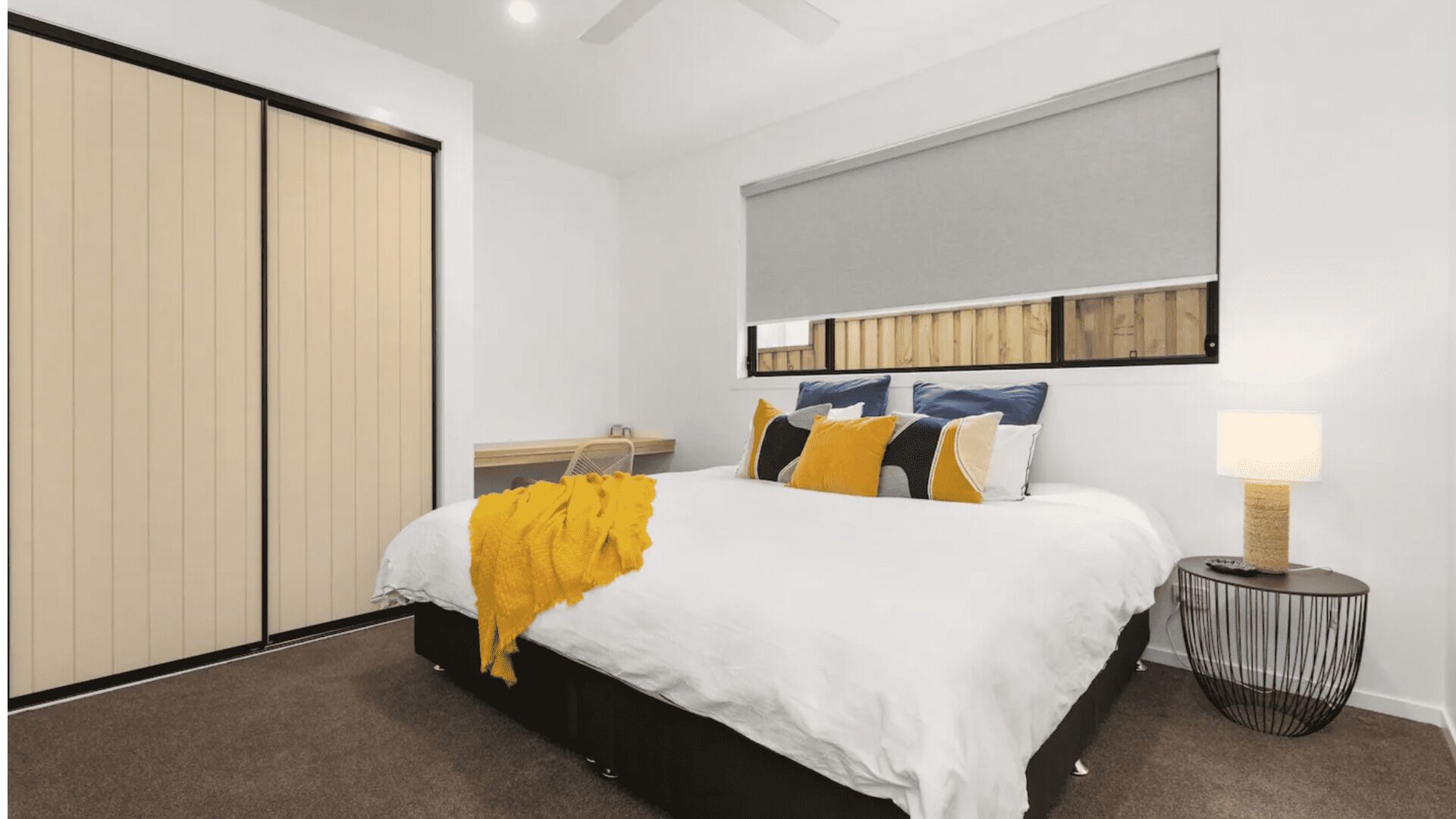 Une chambre à coucher moderne avec un lit, une table de chevet, une lampe et une armoire.