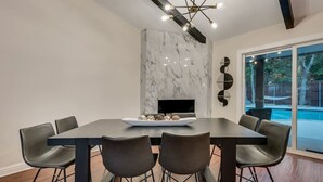 A modern dining room with a marble accent wall, a black dining table, and four chairs.
