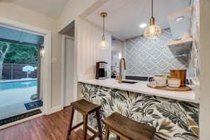 A modern kitchen with a white countertop, two hanging pendant lights, and a patterned backsplash. - FlowerMound · Paradise retreat (Flower Mound)