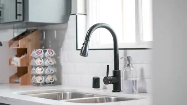 Eine moderne Küche mit einem schwarzen Wasserhahn, einer doppelten Spüle und einem Seifenspender.