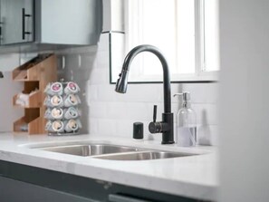 Een moderne keuken met een zwarte kraan, een dubbele spoelbak en een zeepdispenser.