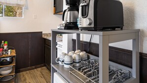 Una zona de cocina con cafetera, tostadora y estante con tazas y escurreplatos.
