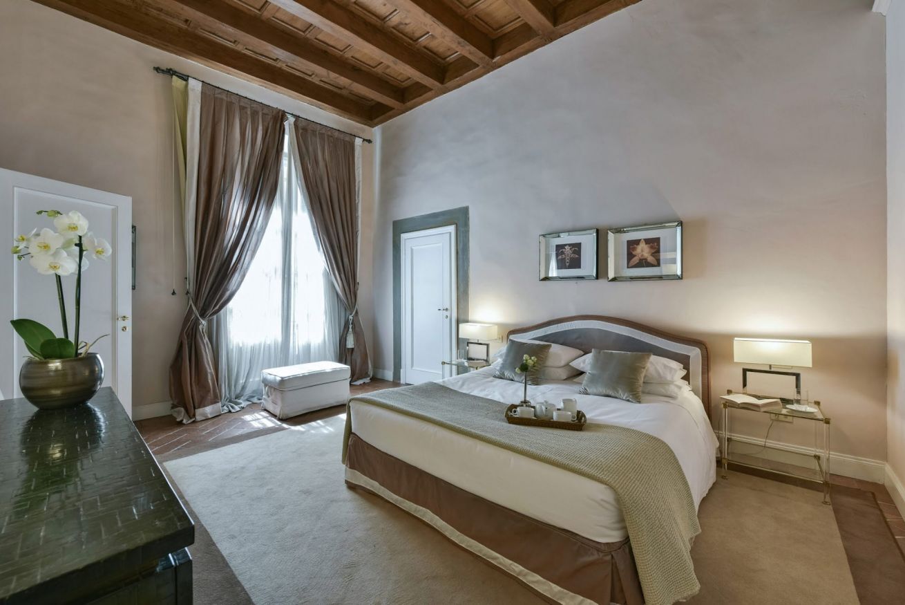 Una camera da letto con un letto grande, comodini, un mobiletto e una finestra con tende.