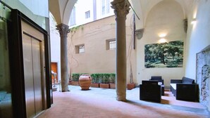 A spacious courtyard with a large planter, a mural, and a seating area. - Boccaccio elegant apartment in Oltrarno (Firenze)