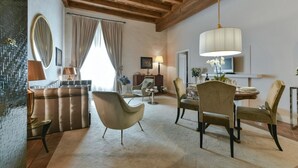 A spacious living room with a high ceiling, a dining area with a table set for four, and a large window with curtains. - Boccaccio elegant apartment in Oltrarno (Firenze)