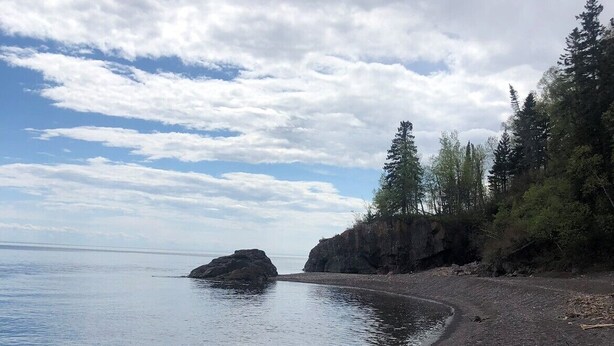 A rocky shoreline with calm water, trees, and a clear sky. - Lola’s Lodge Ski-In/Ski-Out 3 bedroom Lodge near hiking/golf (Lutsen)