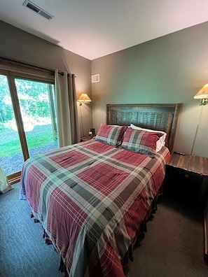 Une chambre avec un grand lit, deux lampes de chevet et une vue sur la verdure.