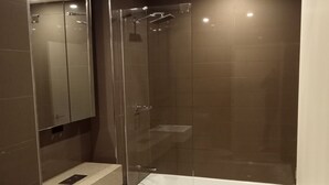 Une salle de bain moderne avec une douche à parois de verre, des toilettes blanches et une baignoire.