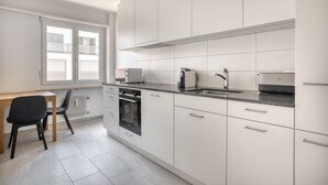A modern kitchen with white cabinets, a built-in oven, a microwave, a coffee maker, and a sink. - Bright Matthäus 3 Room w/ Storage, near Kleinbasel, by Blueground (Basel)