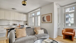 A modern living room with a grey sofa, a round coffee table, and a brown leather armchair. - Upscale Gundelingen 4 Room w/ W/D & Storage, nr Train Station, by Blueground (Basel)