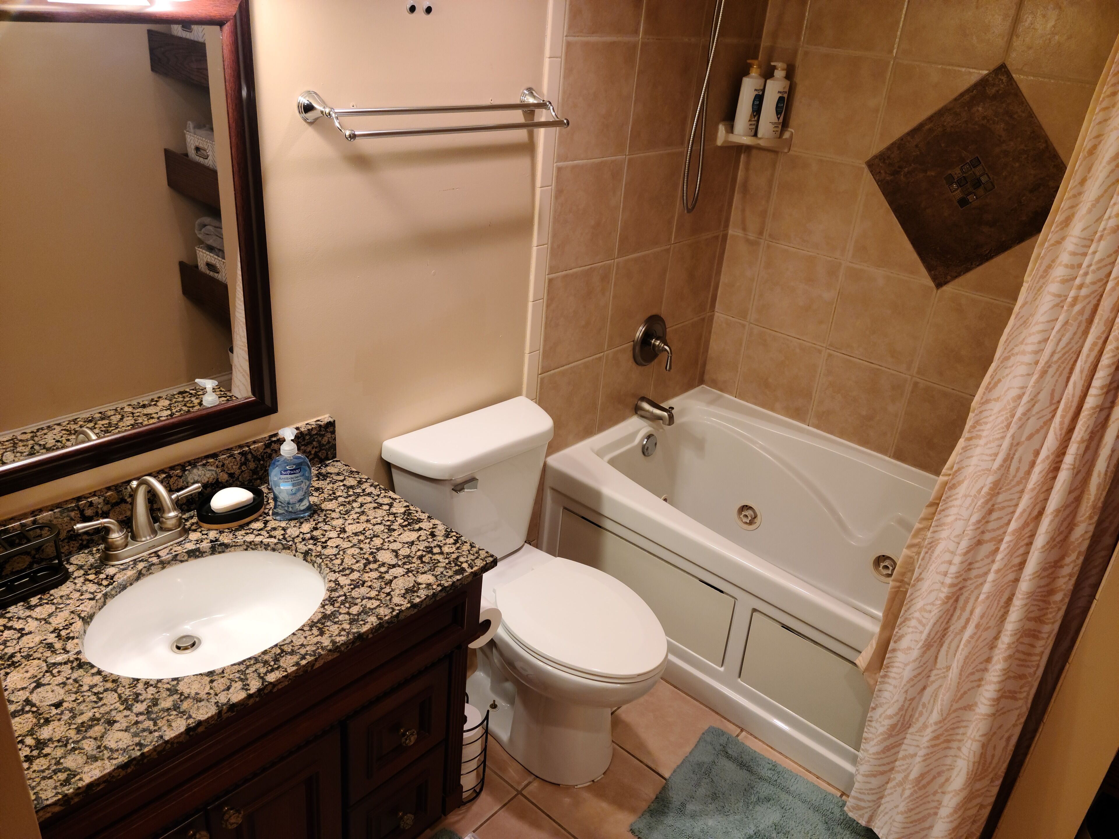 A bathroom with a granite countertop sink, a toilet, and a bathtub.