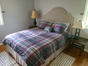 A bedroom with a bed, two nightstands, a lamp, and a window.