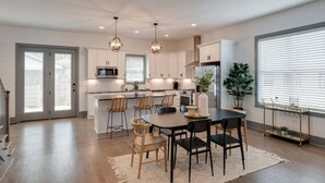 Une cuisine moderne avec des meubles blancs, un îlot central et des luminaires suspendus.