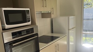 Een keuken met een magnetron, oven en koelkast.