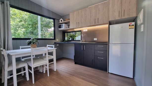 Een moderne keuken met houten kastjes, een ingebouwde magnetron en een roestvrijstalen koelkast.