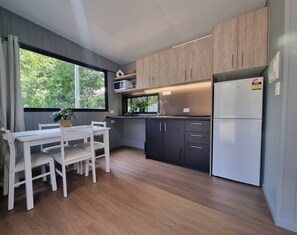 A modern kitchen with wooden cabinets, a built-in microwave, and a stainless steel refrigerator. - Esk Mountain View Lodge (Esk)