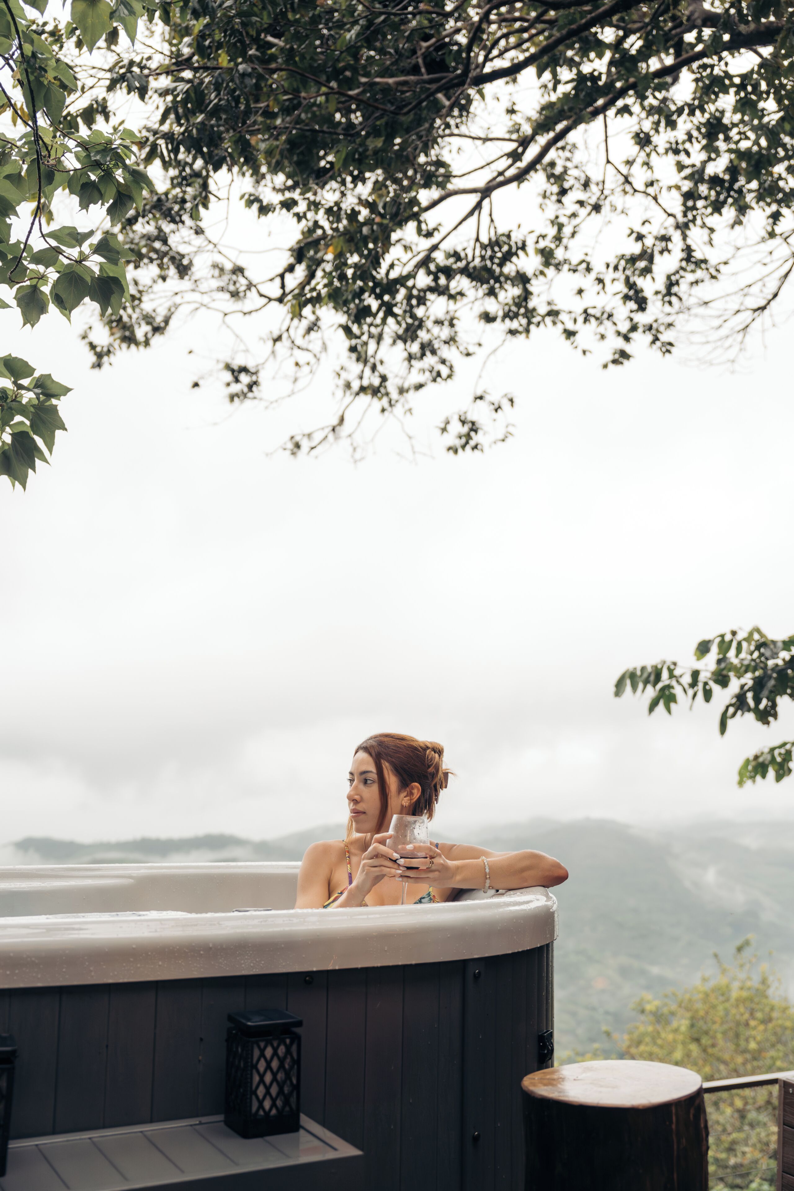 A person relaxing in a hot tub with a mountainous backdrop.