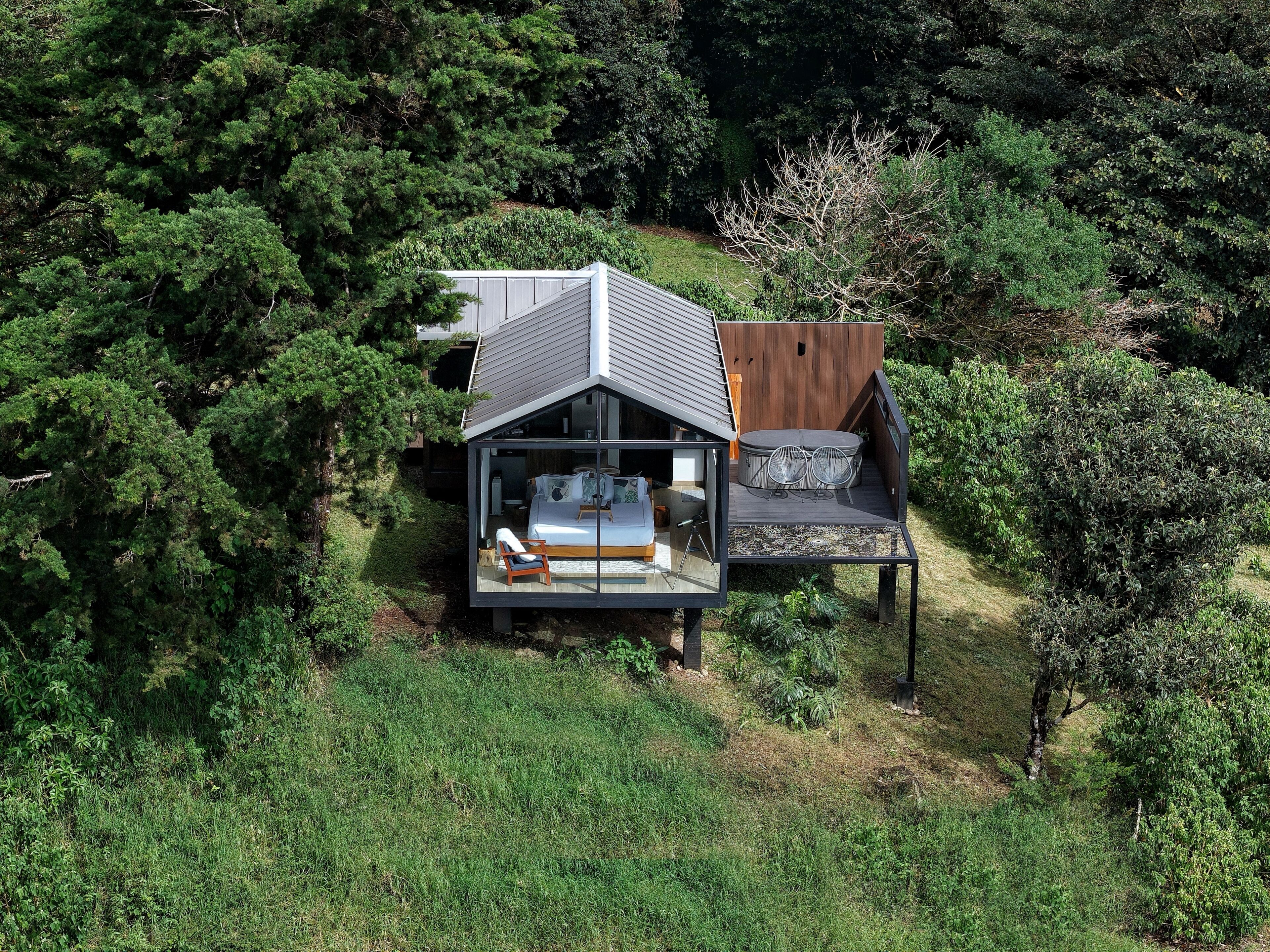 A modern house with a large glass window, a deck, and a hot tub.