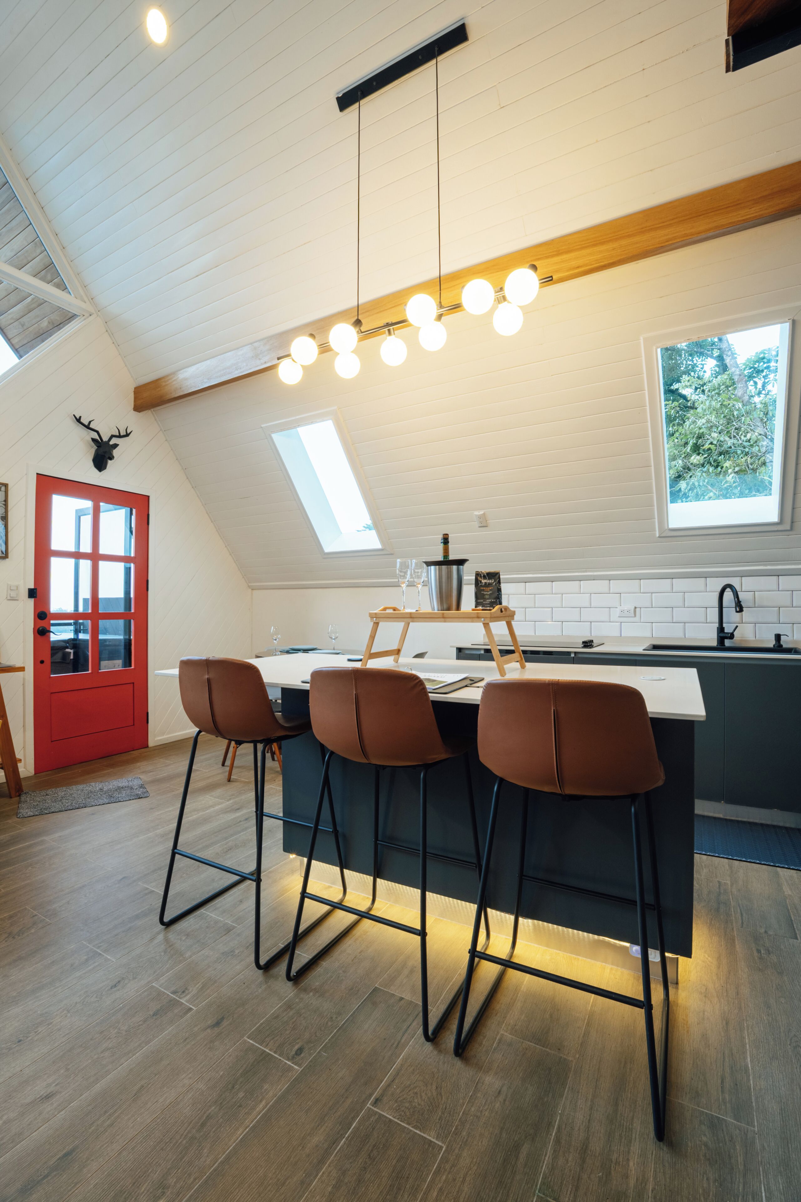 Una cocina moderna con techo de madera, una puerta roja y un tragaluz.