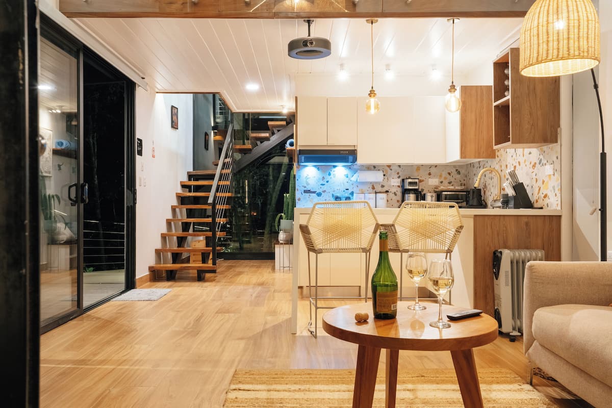 A modern kitchen with wooden cabinets, a built-in stove, and a dining area with a round table.