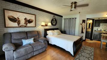 Relax in this serene bedroom with a large bed, sofa, and artwork, perfect for unwinding.