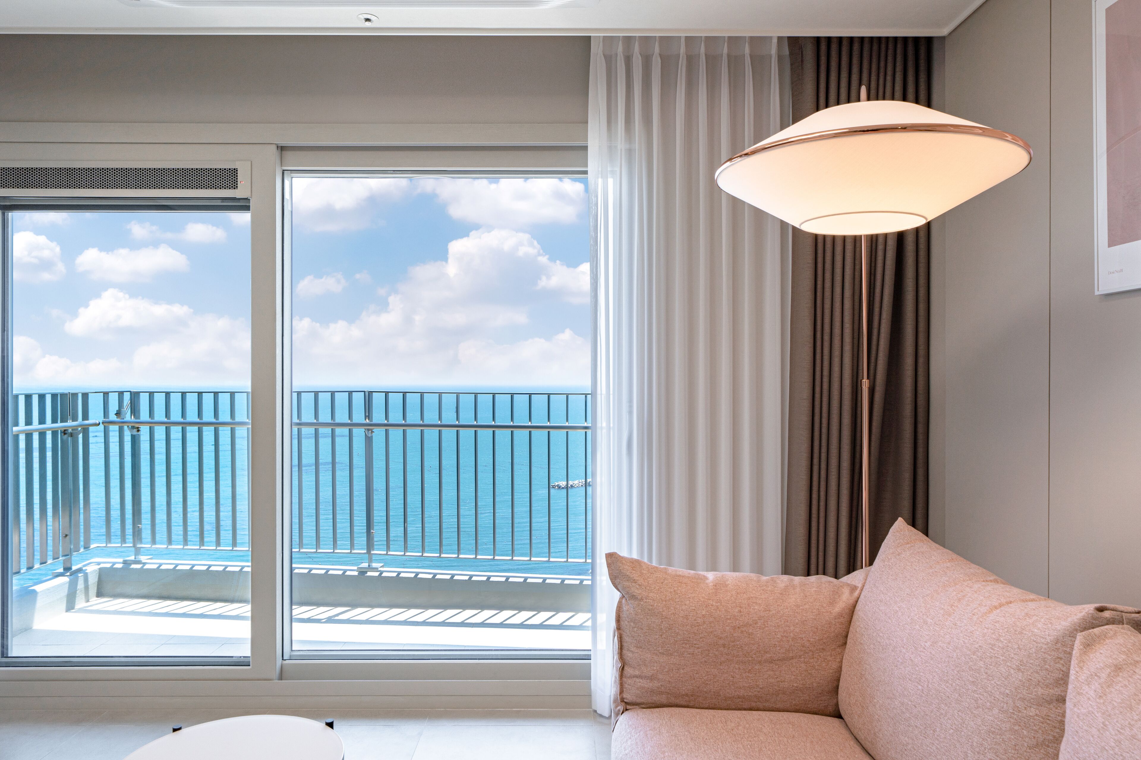 A room with a balcony, a sofa, and a large window with curtains.