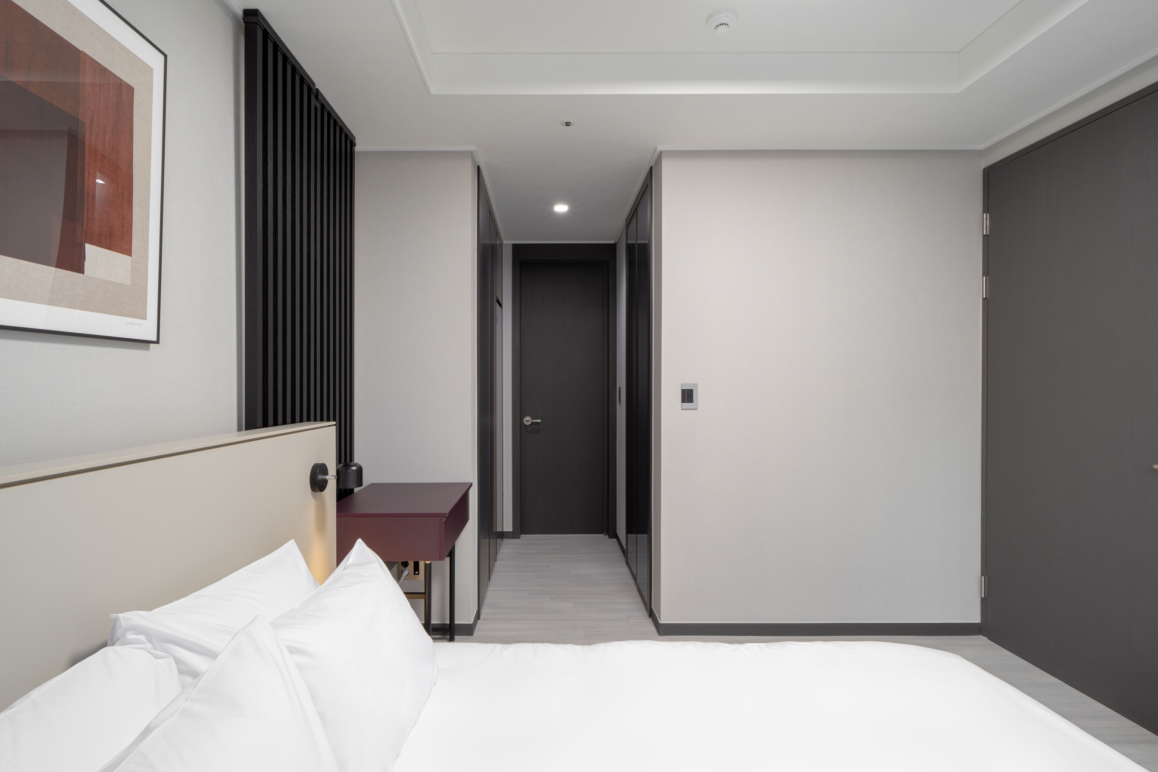 A hotel room with a bed, a desk, and a framed picture on the wall.
