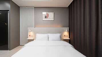 Una habitación de hotel moderna con una cama grande, dos lámparas de noche, una obra de arte colgada en la pared y un radiador.