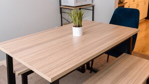 A dining area with a wooden table and blue chairs, a small potted plant, and a microwave in the background. - Builditplace! Kid friendly Stay, Play and Create! (Akron)