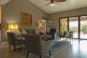 Relax in this spacious living area with a high ceiling, ceiling fan, and large window offering a view.