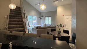 Un salon moderne avec un escalier, un coin repas et une grande fenêtre.