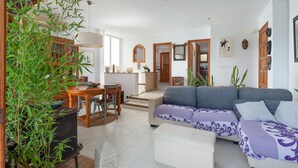 Un grand espace de vie comprenant un canapé, une table à manger et des chaises. Un escalier mène à une autre pièce.