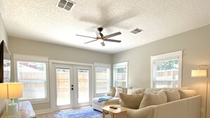 Un salon spacieux avec un canapé blanc, une table basse et un ventilateur de plafond.