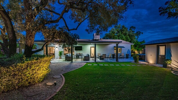 A modern two-story house with a covered patio and a well-maintained lawn.