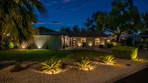 A modern house with a well-maintained lawn, a driveway, and a front yard with palm trees.