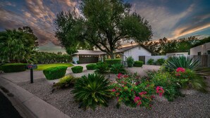 A residential property with a well-maintained garden, a large tree, and a house with a garage.