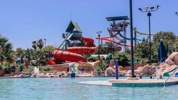 Un parc aquatique doté d’un grand toboggan aquatique, d’une piscine et d’une formation rocheuse.