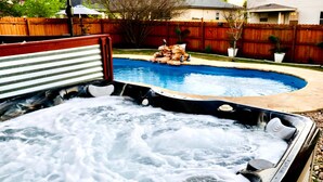 Un bain à remous avec une terrasse en bois et une piscine dans le jardin.
