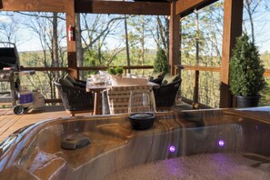 Un bain à remous doté d’un panneau de commande, entouré de fauteuils en osier et d’une table sur laquelle se trouve un verre d’eau.