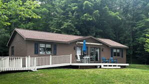 A two-story house with a covered porch, a fenced deck, and a fire pit in the yard. - Lakefront Cottage on South Manistique Lake (curtis)