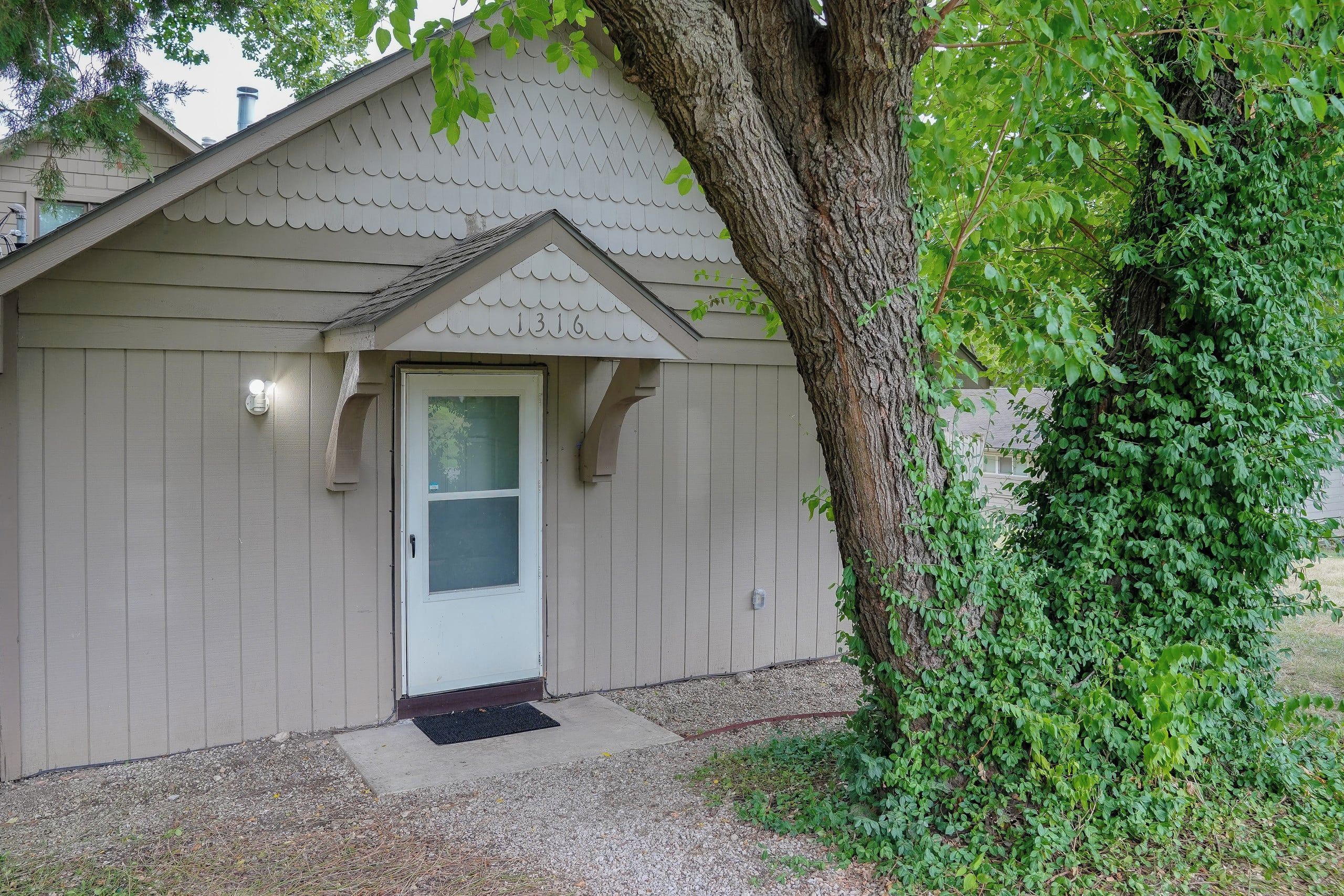 A small, single-story building with a white door and a mailbox.