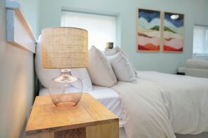 A room with a bed, a nightstand with a lamp, and two paintings on the wall.