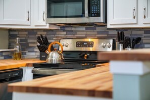 A kitchen with a stainless steel stove, a microwave above it, and a tiled backsplash.