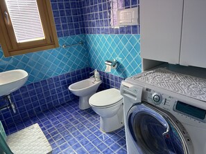 Bathroom features a sink, bidet, and front-loading washing machine.