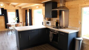 Une cuisine moderne avec des meubles de couleur sombre, une hotte en acier inoxydable, un four à micro-ondes et une cuisinière à gaz.
