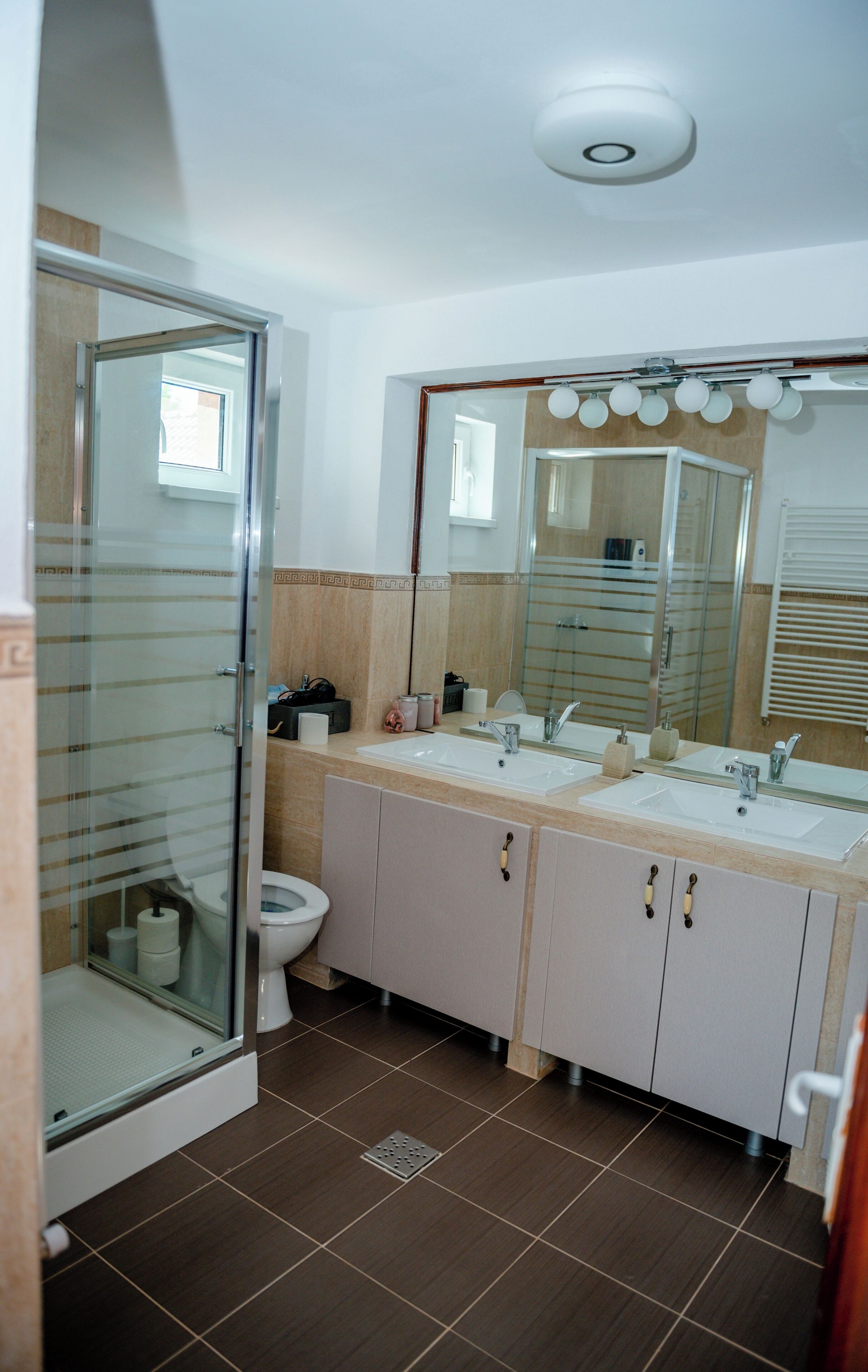 A bathroom with a glass shower enclosure, a toilet, a sink with a mirror, and a towel rack.