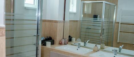 A bathroom with a glass shower enclosure, a toilet, a sink with a mirror, and a towel rack.